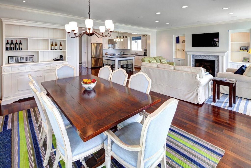 Dining room with blue cushioned chairs, rectangular wood table, and built-in white cabinet.