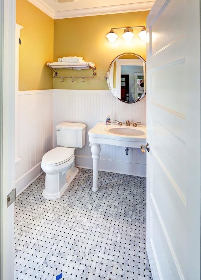 Powder room with a toilet, washstand, and round mirror. 