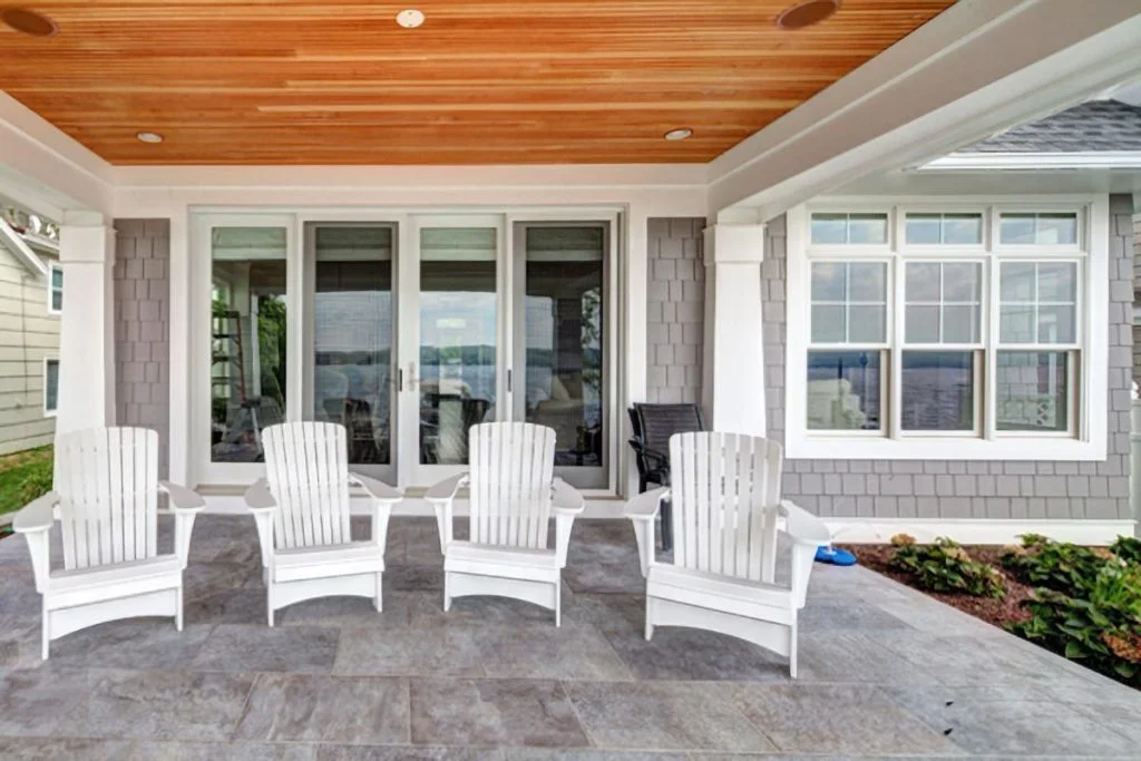 White lounger chairs on concrete flooring of the covered porch.