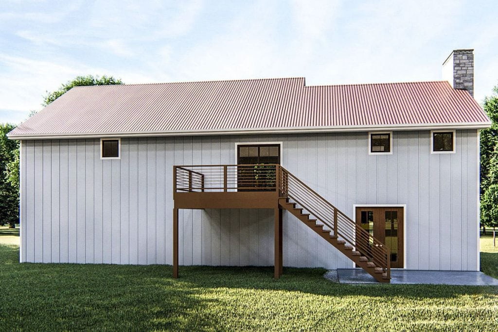 Rear view of the Spacious Post Frame Barndominium shows the stairs from the patio to the deck.