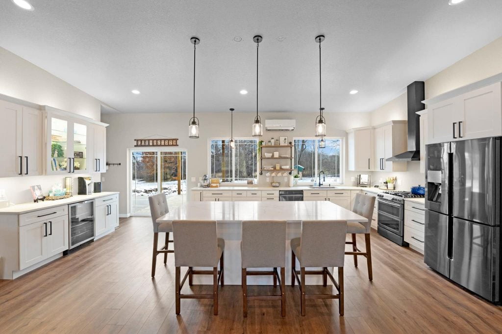elegant u-shaped kitchen equipped with white cabinets and an island and chairs at the center