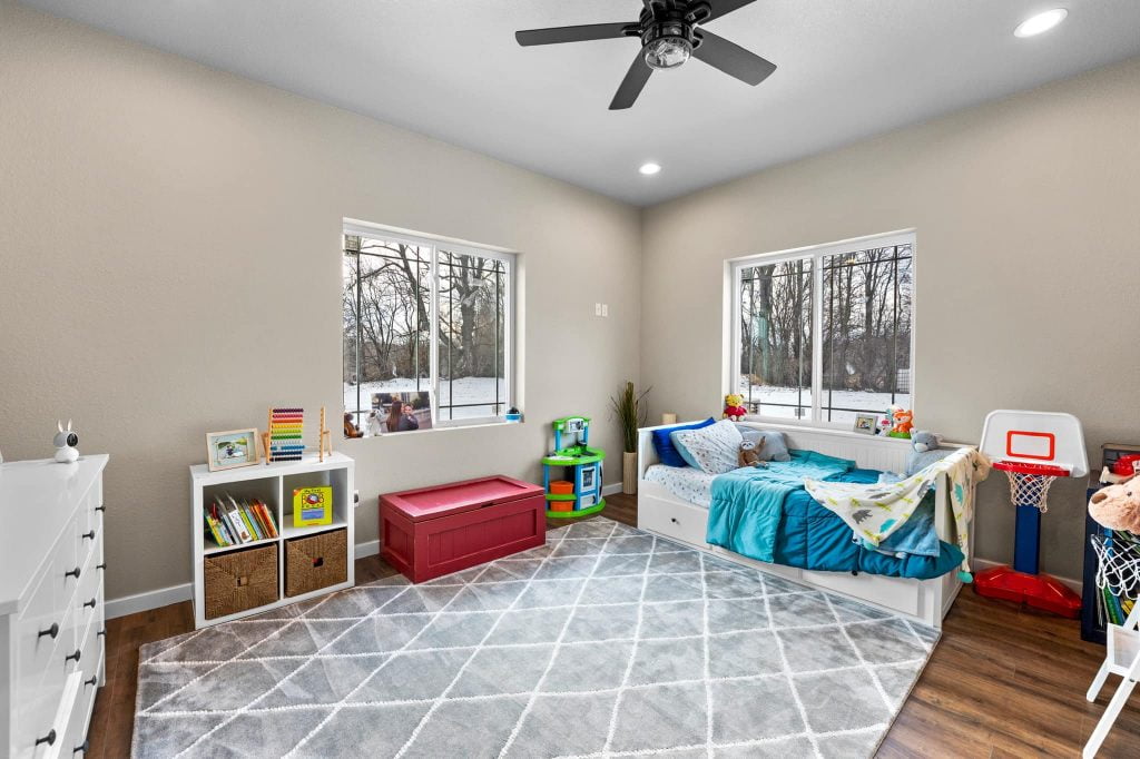 carpeted kid's room with white cabinet, bed and glass windows