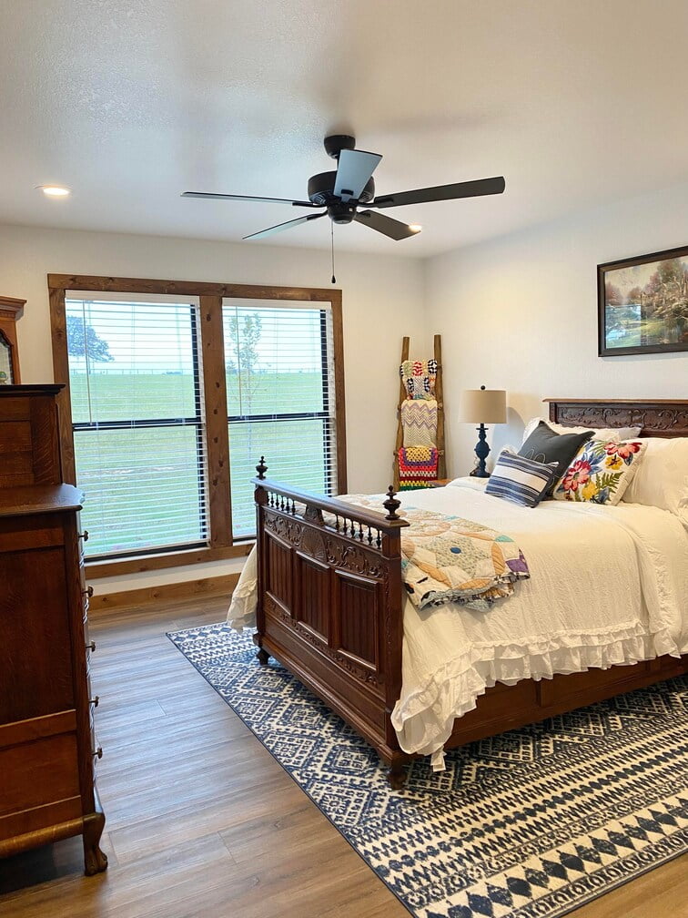 A comfy bedroom in Chris and Brandi's Barndominium, well lit by ceiling lights and window.