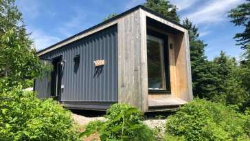 grey metal shipping container turned into a home with timber siding