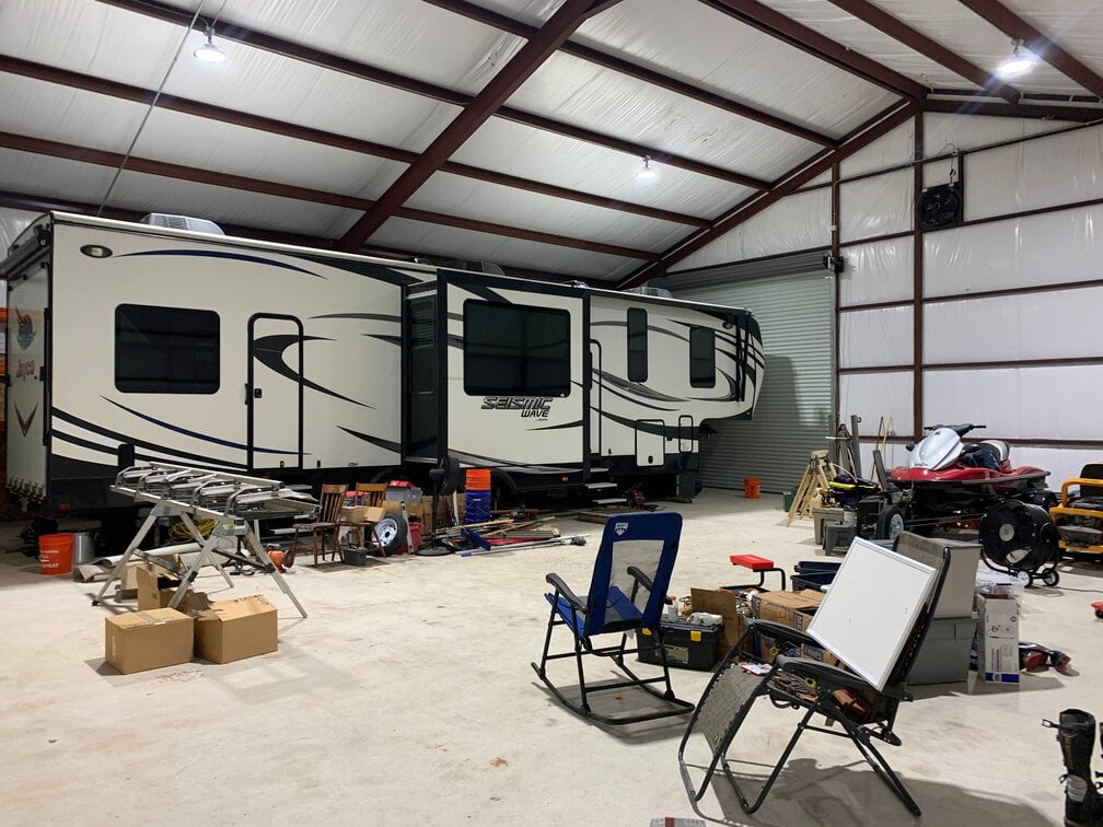 messy garage with an RV trailer