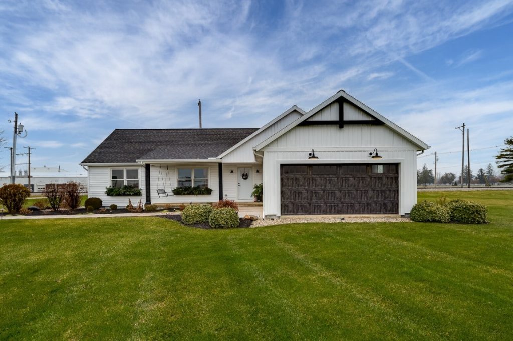 A single story white home with a brown roof, featuring a large garage on the side. The house has a clean and modern look, with the garage providing ample storage space for vehicles or other items.