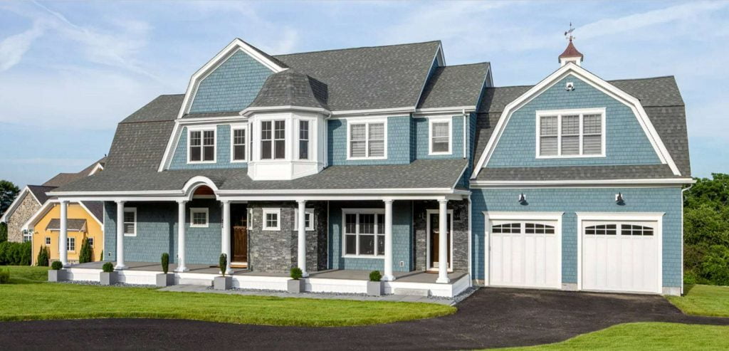 A two-story home with an elegant and captivating design, featuring a teal green exterior, high ceilings, and a two-car garage. The house has a modern and minimalist design with clean lines and a unique color, set against a rural background.