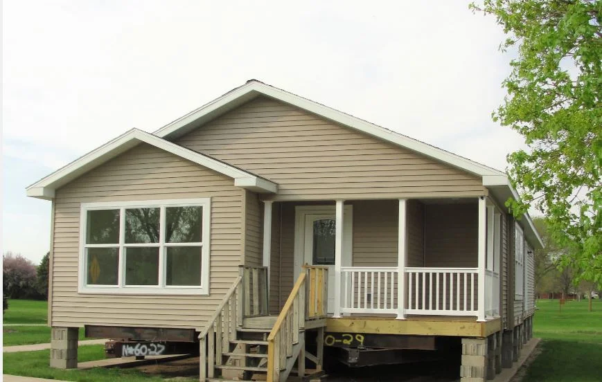 An elevated, modular home with a cream colored finish