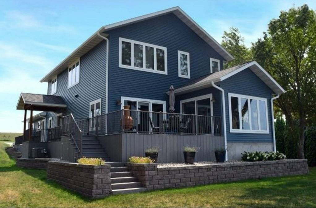 A home with high ceilings, featuring a blue exterior and bricks walls. The house has a rustic and inviting feel, with the high ceilings providing a feeling of grandeur and spaciousness. The blue color of the exterior and the bricks walls give it a unique and charming appearance, set against a natural background. The combination of the high ceiling, blue and bricks walls give it a timeless and elegant look.