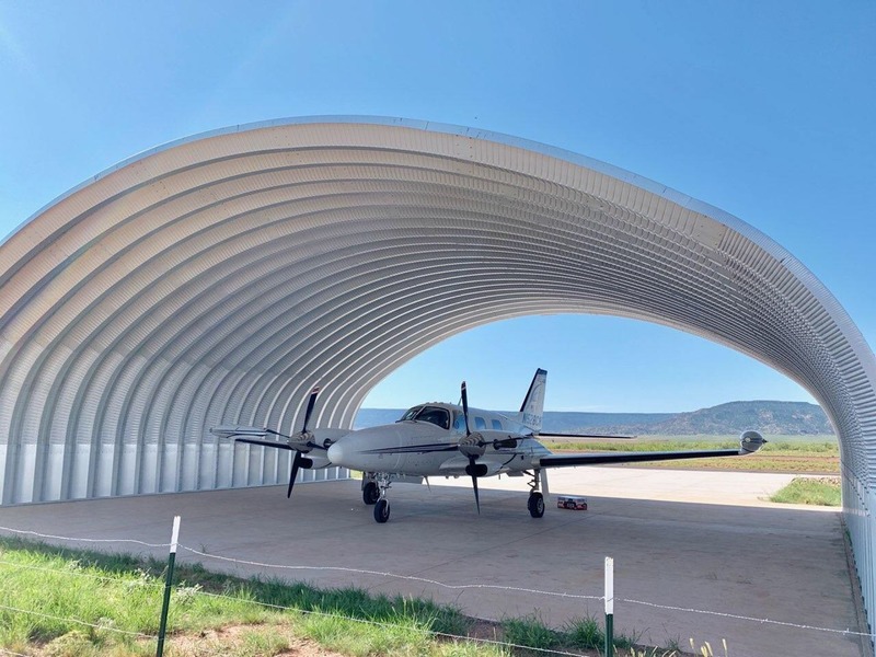 A large aircraft hangar providing a home to a small plane. 