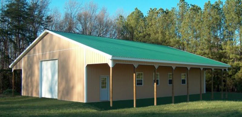 An image of a charming peach agricultural barndominium with a verdant green roof. The building features small windows and a central white door that opens onto a welcoming porch. The warm peach color adds a touch of elegance to the practical design of the building.