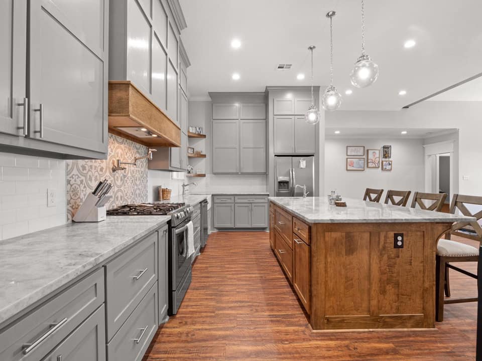 A photograph of a kitchen with a natural wood island situated on a hardwood floor. The island is crafted from raw, unfinished wood, with visible knots and grain patterns adding character and texture to the piece.