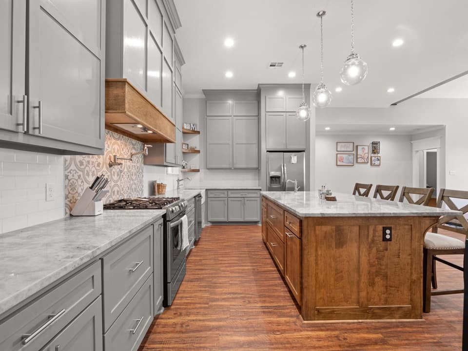 A photograph of a kitchen with a natural wood island situated on a hardwood floor. The island is crafted from raw, unfinished wood, with visible knots and grain patterns adding character and texture to the piece. 