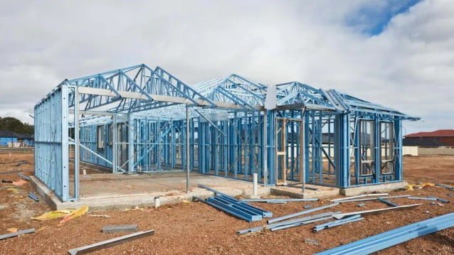 A blue steel frame home with a grey concrete foundation under construction