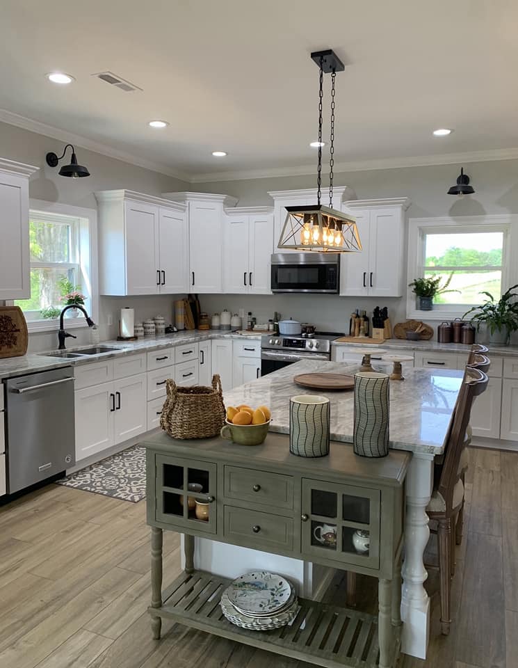 A cozy kitchen with a bright and vibrant atmosphere. The kitchen features white cabinets with modern brushed steel handles and a marble countertop with grey veining