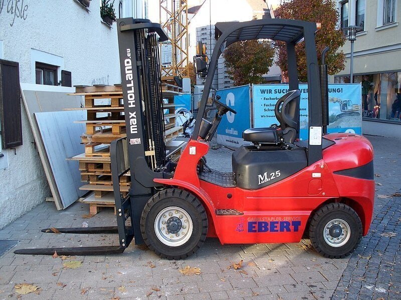 A robust counterbalance forklift stands tall against a warehouse backdrop. The heavy-duty machine boasts a sturdy frame with a large set of dual rear.