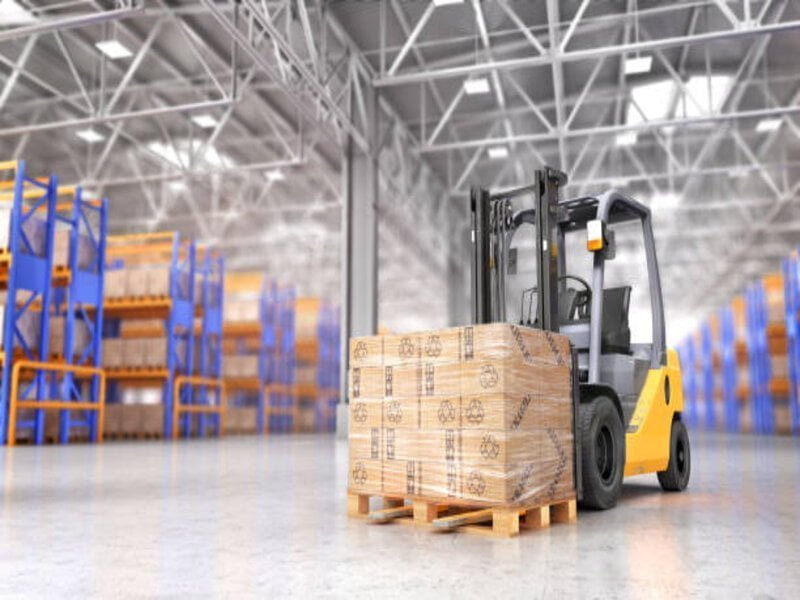 A yellow order picker forklift positioned in a spacious warehouse aisle.