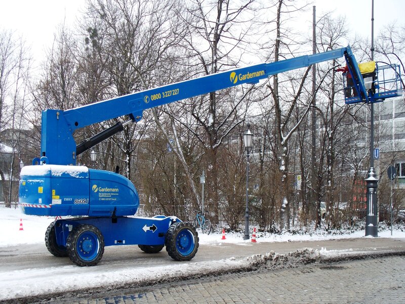 A telescopic boom lift standing tall against a clear blue sky. 