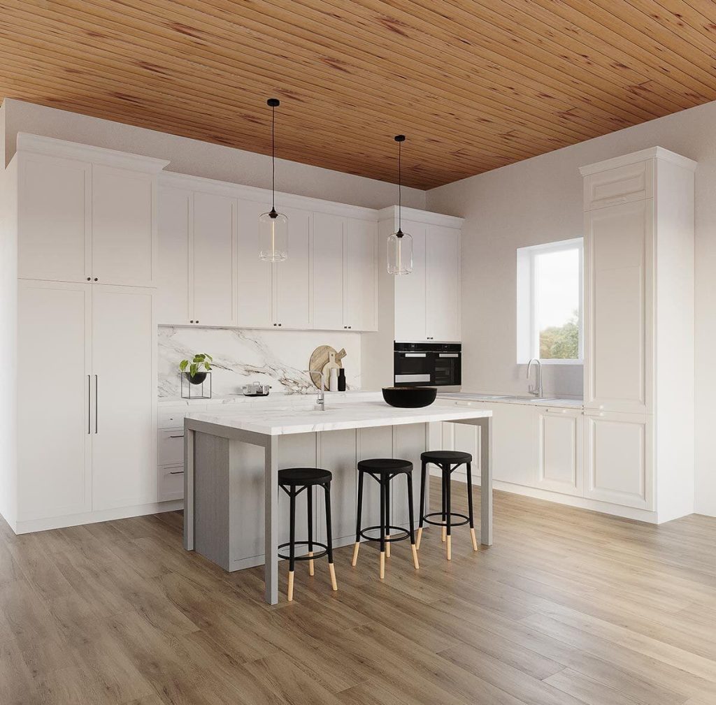 Image depicts a spacious kitchen and dining area characterized by an L-shaped layout. A substantial island counter takes center stage, providing both work surface and informal dining space, complete with three high chairs positioned for use. 