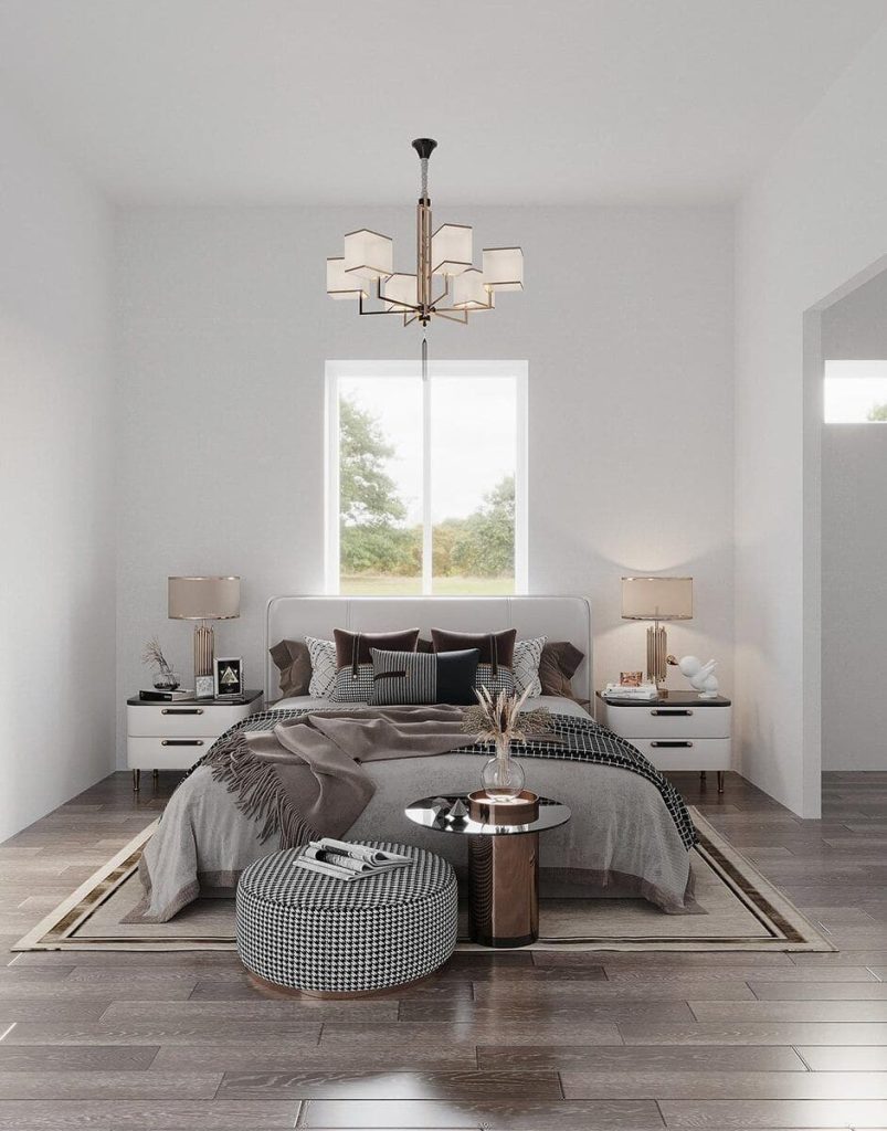 An elegant master bedroom featuring a grand chandelier hanging from the ceiling, providing warm illumination over a large, plush bed. The bed is nestled between two stylish nightstands, each adorned with bedside lamps and accessories. The interior design exudes luxury and comfort.