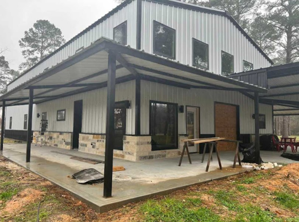 A white and black barndominium with a wrap-around porch. Image via Barndominium Living Facebook group by Tanya M.