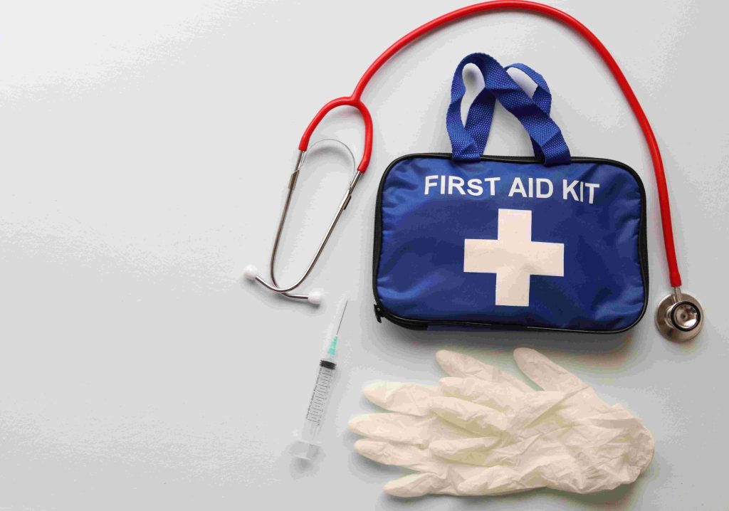 A blue first aid kit, white gloves, syringe, and red stethoscope