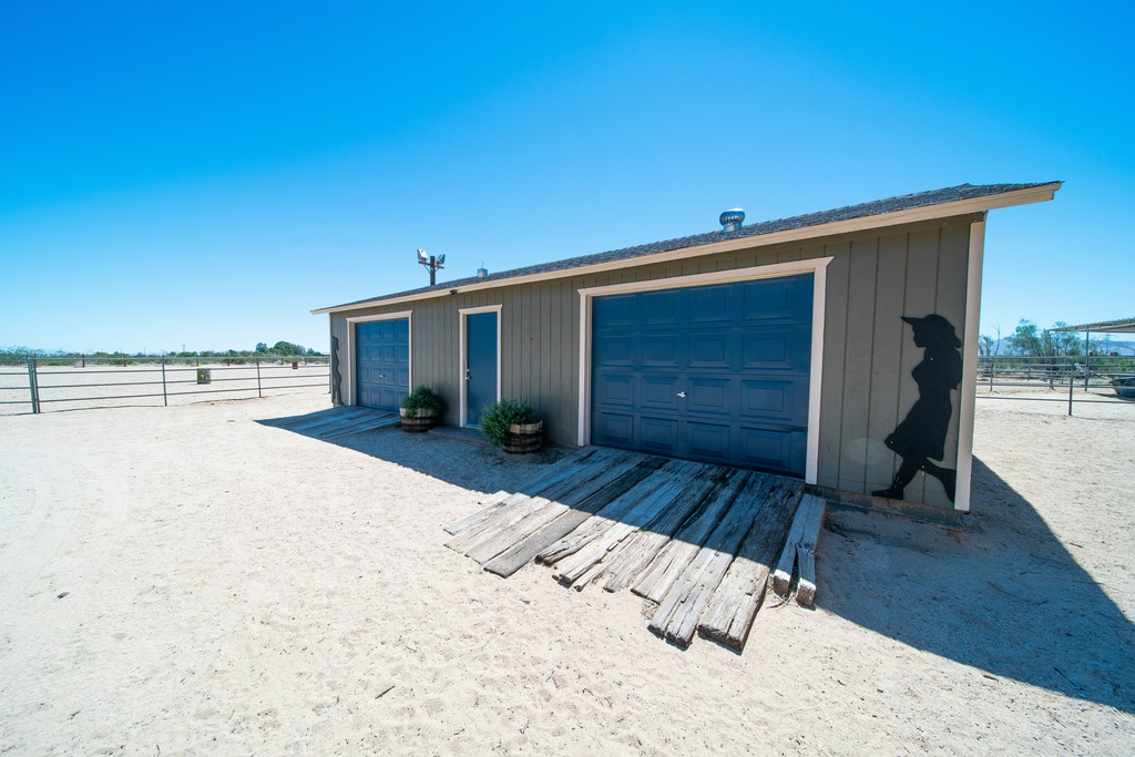 A large blue and grey metal garage in an expansive sandy area