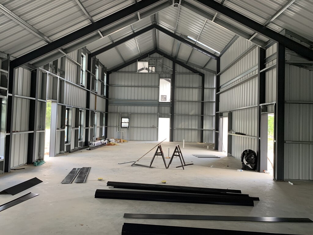 A black and white steel-framed barndominium with walls under construction