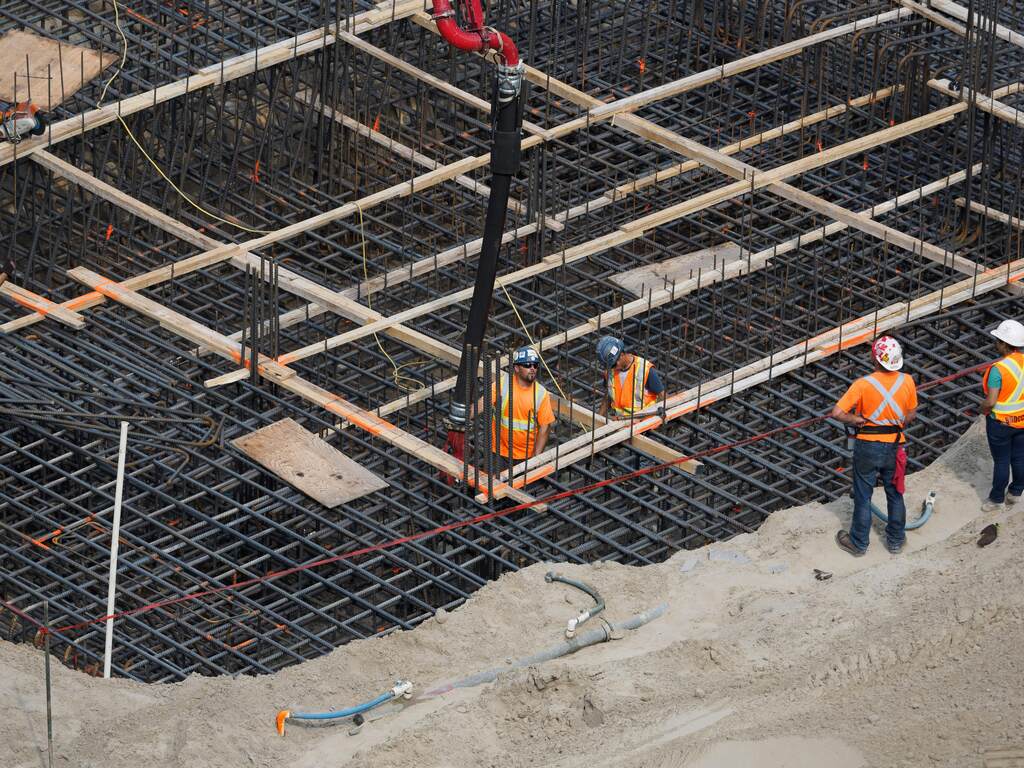 4 construction workers in protective gear building a steel frame structure